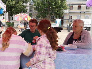 Kinder und Erwachsene sitzen unter einem Pavillon.