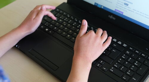 Aufgeklappter Laptop, Schüler Laptop. Kinderhände tippen auf der Tastatur des Laptop.