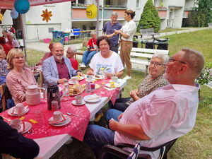 Fest. Menschen sitzen an Kaffeetafeln unter geschmückten Pavillons.