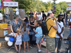 Draußen. Menschen, Erwachsene und Kinder bei einem bunten Fest. Zwei AWO Pavillons und Luftballons sowie Fahnen von regionalen Wohlfahrtverbänden.