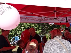 Ein AWO Pavillon. 4 Kinder und 6 Erwachsene stehen darunter. Bunte Luftballons sind am Pavillon befestigt: Kinder sind unsere Zukunft steht auf einem Luftballon.