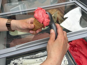 Eiswagen. Jemand macht eine große Kugel rotes Eis in eine Eiswaffel.