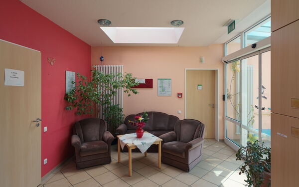 Polstersitzgruppe, Zwei Sessel, ein kleines Sofa dunkelgrau in der Mitte ein Tisch mit Blumenvase.