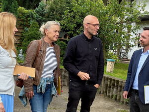 2 Frauen und 2 Männer draußen. Rechts im Hintergrund ein weißes Haus.