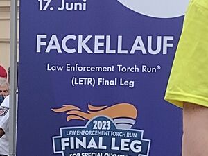 Ein Schild der Special Olympics World Games Berlin 2023        14. bis 17. Juni.        Fackellauf            und ein Logo mit brennender Fackel