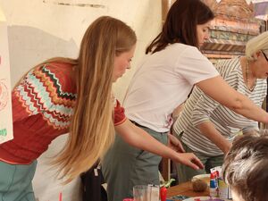 Drei Frauen stehen nebeneinander an einem Tisch. Basteltisch.