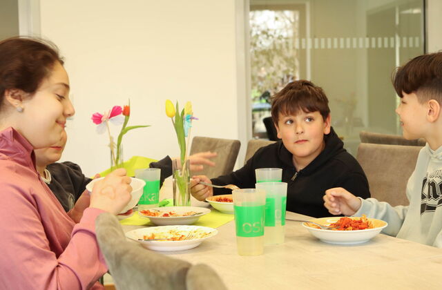 2 Mädchen, 2 Jungs am Tisch beim gemeinsamen Essen.
