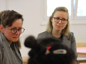 3 Frauen sitzen um einen Tisch.