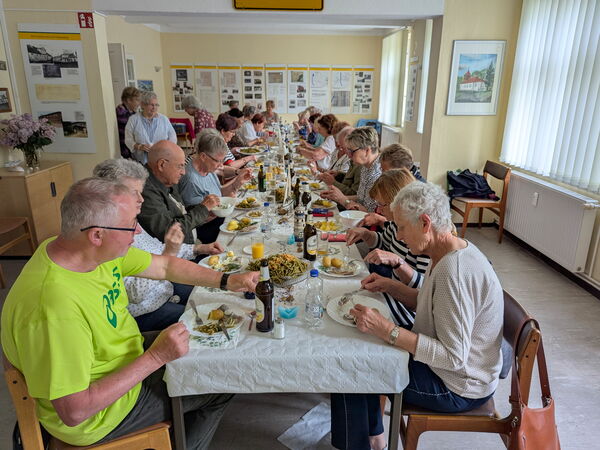 Gedeckte lange Tafel. Menschen die Matjes essen.
