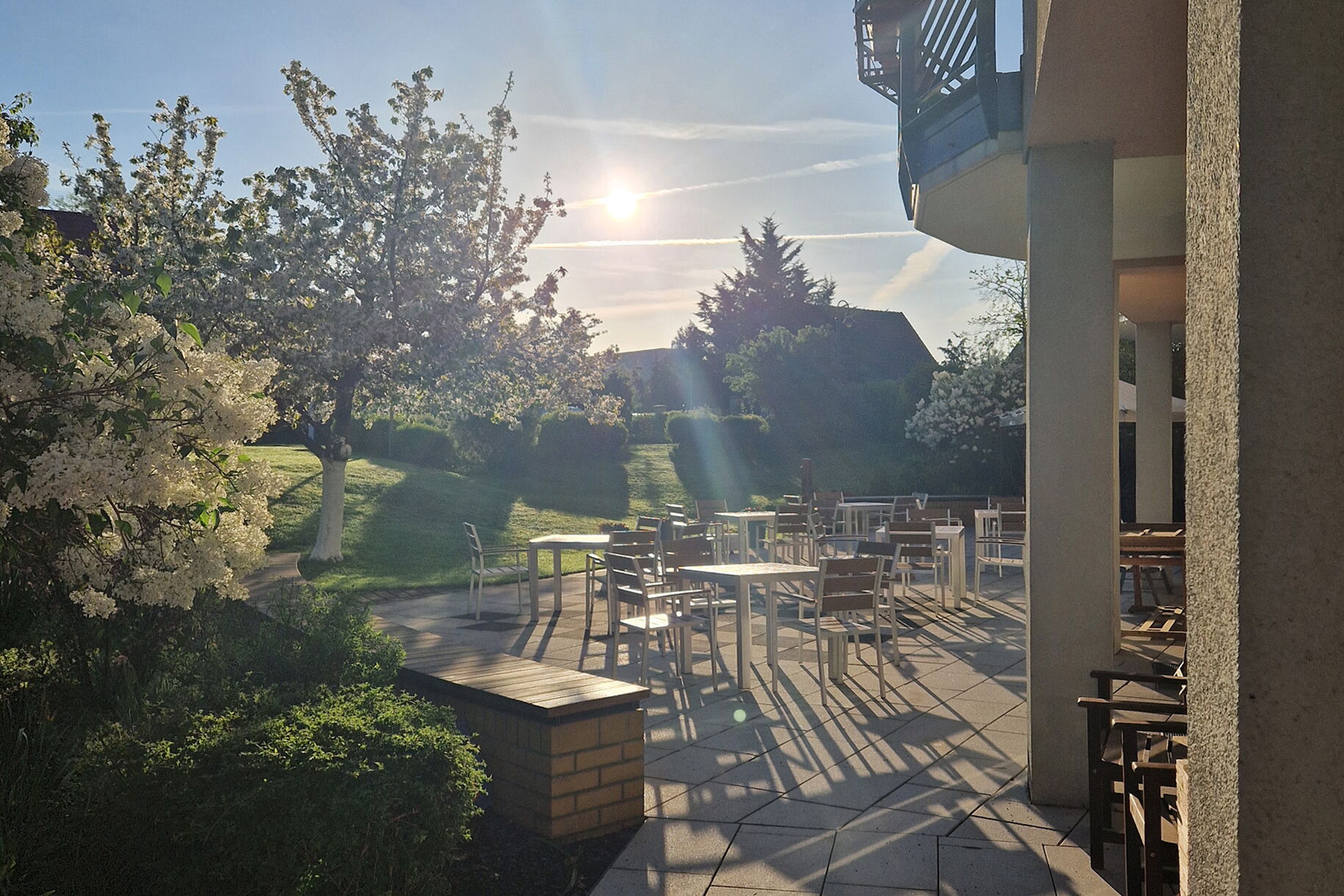 Sonnenüberflutete Terrasse Mit Stühlen und Tischen.