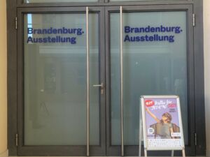 Geschlossene Eingangstür zur Brandenburg-Ausstellung. Davor steht ein Aufsteller von Kultur für Jeden.