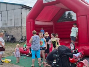 Rote Hüpfburg mit AWO Logo. Spielende Kinder auf und vor der Hüpfburg.