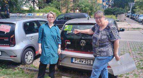 2 Frauen stehen hinter einem AWO Dienstwagen. Ein grüner Aufkleber auf der Rückscheibe: Diese Auto fährt nicht mehr, wenn...