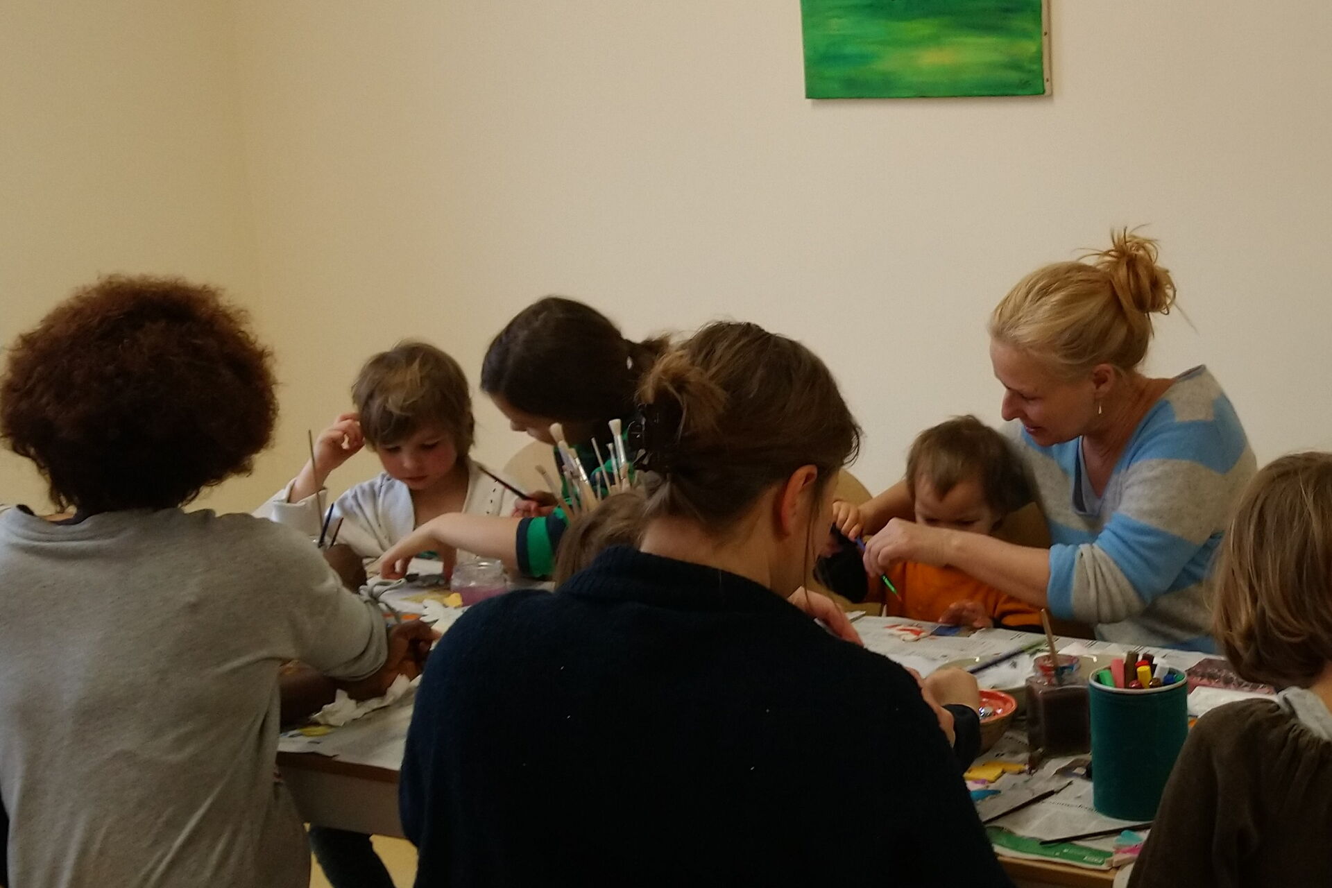 Kinder an einem Tisch, die malen. Erwachsenen unterstützen.