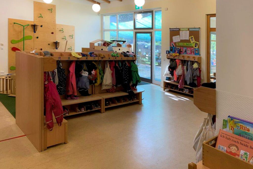 Mehre Garderoben, da hängen Jacken und Beutel und in einem Fach darunter stehen die Schuhe der Kinder.