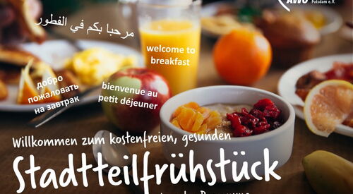 Ein Frühstückstisch mit Schalen voll Obst, einem Glas Orangensaft, Brötchen und Marmelade. Text im Bild: „Willkommen zum kostenfreien, gesunden Stadtteilfrühstück.
