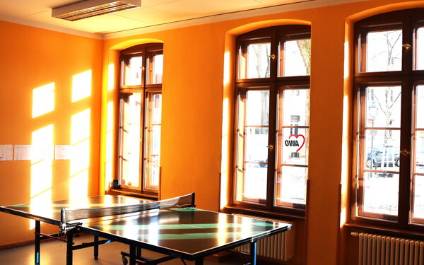 Großer Freizeitraum mit Tischtennisplatte. Große Fenster lassen viel Sonnenlicht rein.