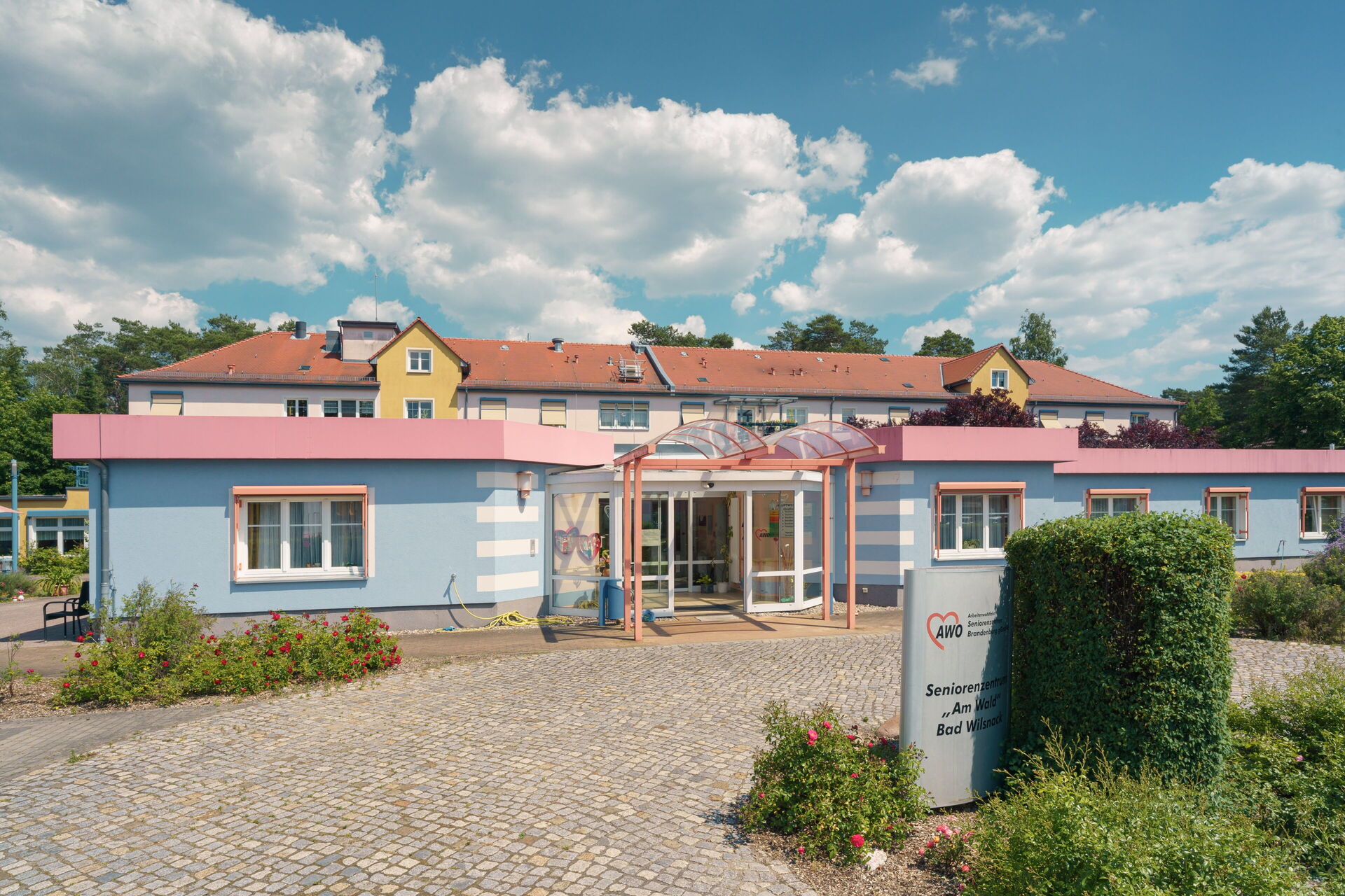 Front des Seniorenzentrums. Haupteingang. Davor gepflasterte Straße.
