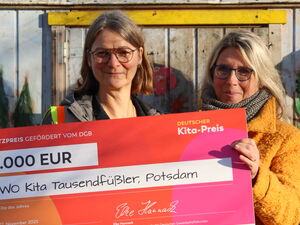 2 Frauen halten einen großen Preis-Scheck in die Kamera und lächeln. Preisgeld: 2.000 Euro.