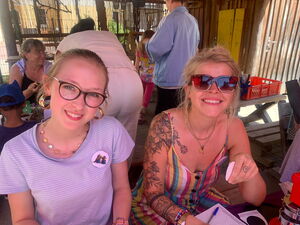 2 sommerlich gekleidete blonde Frauen lächeln in die Kamera.