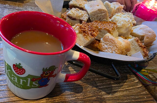Kaffee in einer Tasse vom Karls Erlebnishof und ein Teller mit Kuchenstücken.