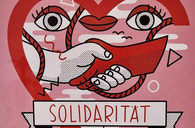 Plakat: Rosa, rotes Herz, zwei Hände die sich die Hand geben, eine rot und die andere weiß, zwei Augen und ein Mund in der Herzform. Darunter steht in Großbuchstaben: Solidarität