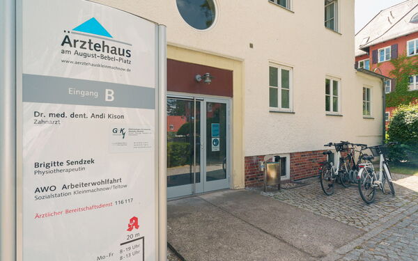 Eingang vom Ärztehaus, ohne Stufen. Schild vom Ärztehaus steht draußen links neben dem Eingang.