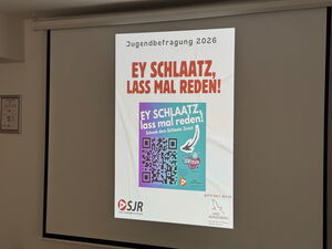 Leinwand in einem Raum, darauf projiziert: "Jugendbefragung 2026 - Ey Schlaatz, lass mal reden" und ein QR Code