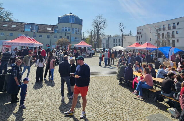 Totale. Ganzer Platz. AWO-Pavillons sind verteilt, Menschen sitzen recht im Bild auf Bänken, sonst frohes Markttreiben.