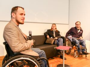 Udo Sist von Normalo TV und selbst Rollstuhlfahrer führt auf der Bühne ein Interview mit Menschen mit Behinderungen zu ihren Erfahrungen im Arbeitsleben.