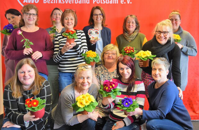 Viele Frauen halten Blumen in Richtung Kamera.