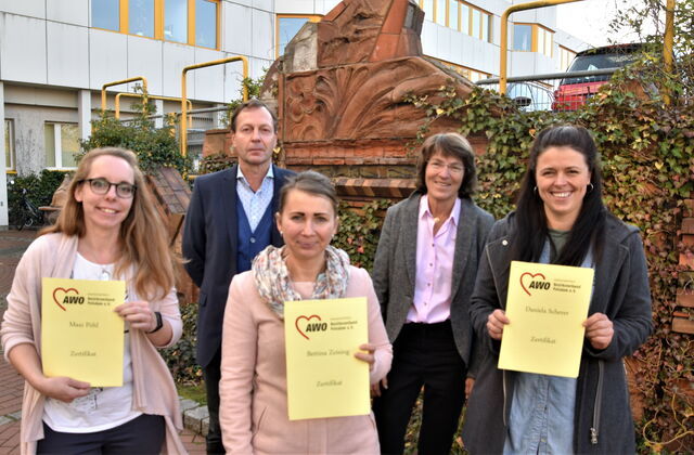 Auf dem Bild sind zu sehen im Vordergrund Bettina Zeising, Daniela Scherer und Maxi Pöhl, die ihre Zertifikate als Schulgesundheitsfachkräfte in der Hand haltern. Dahinter Stefan Zaborowski, Verantwortlich beim AWO Bezirksverband für die Zertifizierung