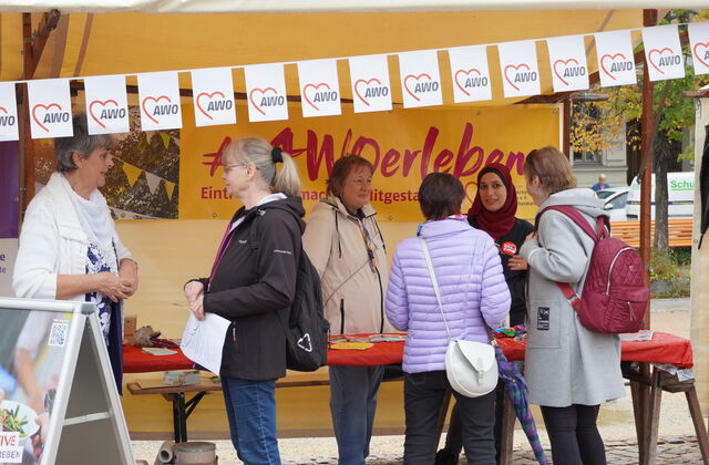 AWO erleben Stand mit gelben Banner. Menschen beraten interessierte Ehrenamtssuchende.