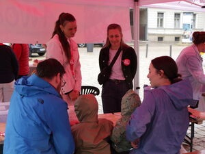 Menschen sitzen und stehen unter einem Pavillon.