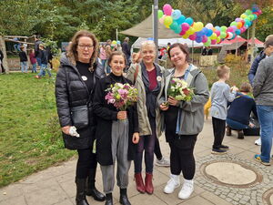 Kleines Gruppenfoto im Freien. Vier Frauen, zwei haben Blumensträuße in der Hand.