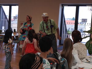 Eltern und Kinder essen gemeinsam in der Kantine. Klinikclowns albern rum.