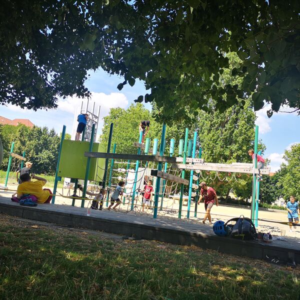 Spielplatz. Großes Klettergerüst. Die Sonne scheint. Kinder die klettern und spielen.