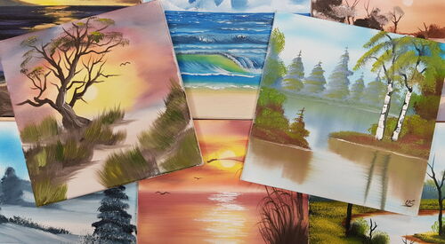 Mehrere bunte Landschaftsbilder im Stil von Bob Ross liegen überlappend auf einem Tisch.