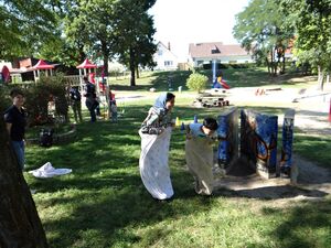 Junge und Frau beim Sackhüpfen. Sonne scheint, im Hintergrund ist ein Spielplatz.