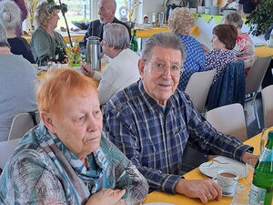 Ältere und alte Menschen sitzen an Tischen und trinken Kaffee.