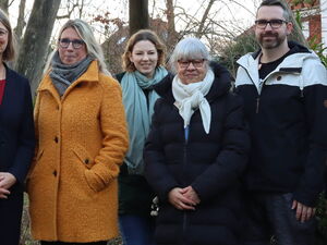 Gruppenbild: 5 Frauen und 2 Männer stehen draußen unter einem großen Holzschid mit der Aufschrift: "AWO Kita Tausendfüßler".