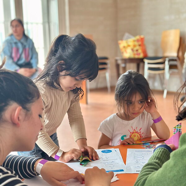 Kleine Mädchen an einem kleinen Tisch mit Zetteln.