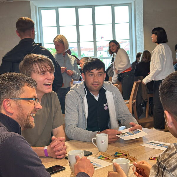 Gesellige Runde. An einem Tisch sitzen Männer und lachen.