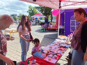 Unter einem AWO-Pavillon stejht ein langer Tisch mit info-Material. Eine ältere Frau steht davor und sieht sich etwas an.