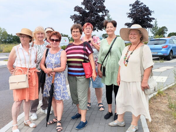 Gruppenbild: 8 sommerlich gekleidete Frauen auf einem Gehweg an einer Straße.