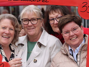 4 Frauen lächeln durch einen roten Bilderrahmen, den sie vor sich halten. In der oberen rechten Ecke steht eine 35.