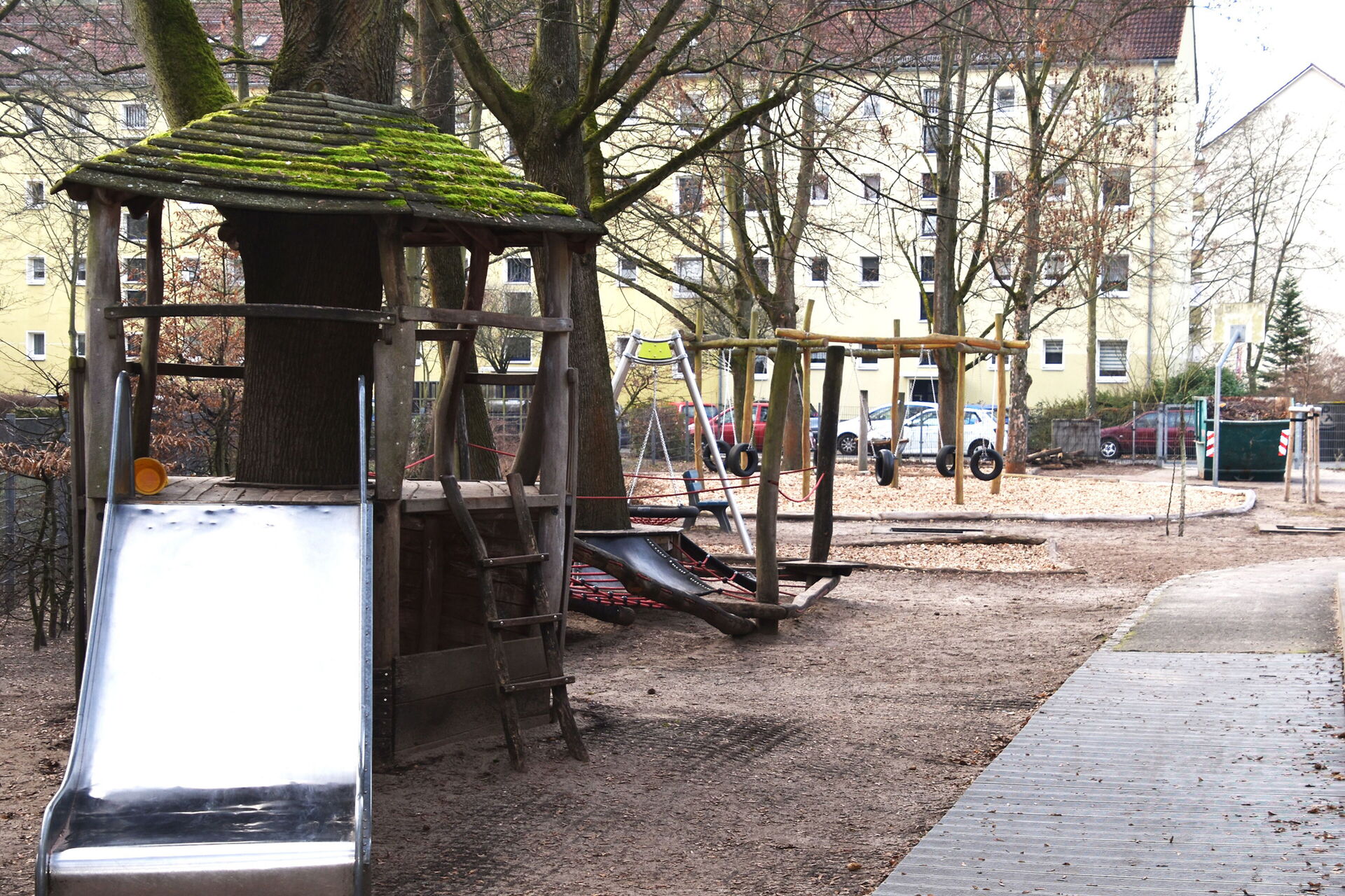 Draußen, Spielplatz, Kleines Klettergerüst mit Rutsche. Reifen-Schaukel mit mehren Reifen die an Ketten hängen.
