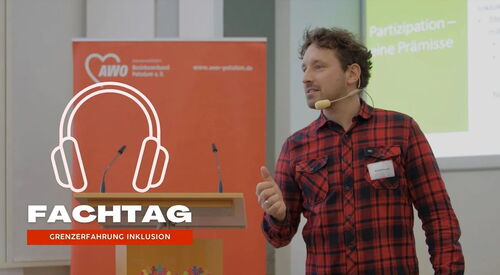 Redner mit Mikro am Mund. Mann trägt rot-schwarz kariertes Hemd, dunkle Jeans und hat dunkle Haare. Dahinter ein Rednerpult. Ein Audio-Symbol in Form von Kopfhörern ist im Bild.  Text darunter: Fachtag - Grenzerfahrung Inklusion