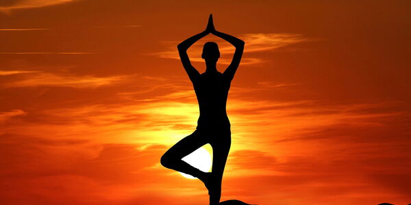 Hier sehen sie eine Figur die vor einem roten Himmel Yoga-Übungen macht