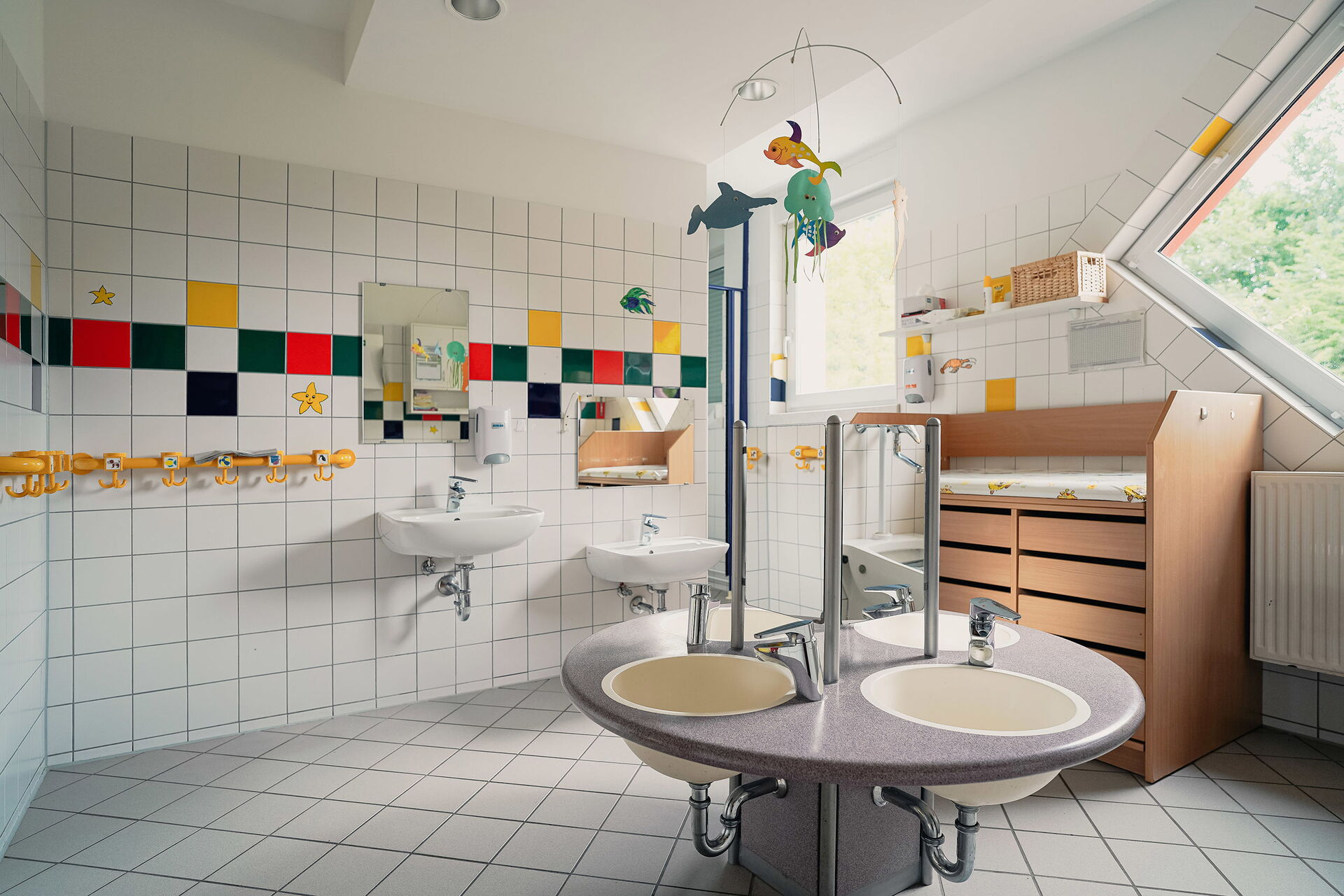 Gefliestes Bad mit Waschbecken und Wickel-Kommode.